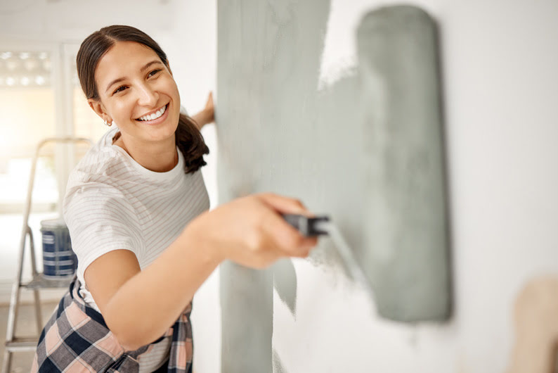 jeune-femme-en train-de-peindre-un-mur-dans-un-appartement-loue-a-un-proprietaire